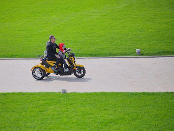 Man with son riding bicycle on footpath