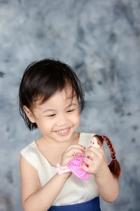 Portrait of happy charming 4 years old cute baby asian girl, little child playing with a doll.