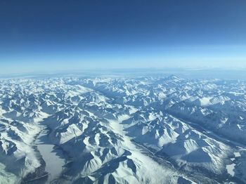 Aerial view of snowcapped mountains against blue sky