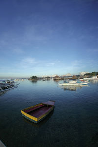 Sailboats moored on river against sky in city