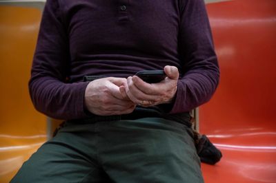 Low section of man sitting against yellow wall