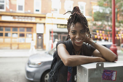 A young woman leaning against a metal box.