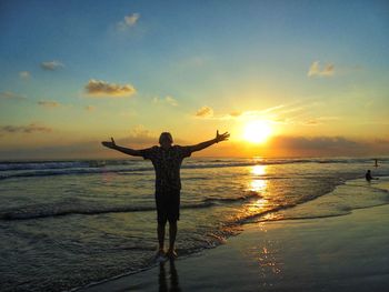 Silhouette man standing at beach against sky during sunset