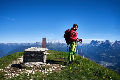 Male hiker standing on mountain against blue sky