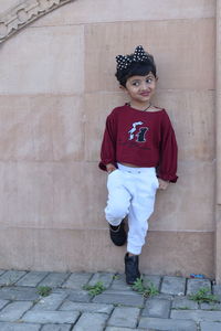 Portrait of cute boy looking away against brick wall