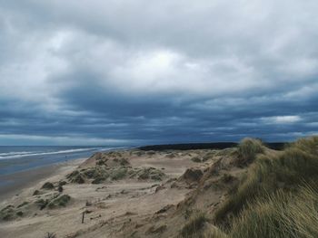 Scenic view of beach against cloudy sky