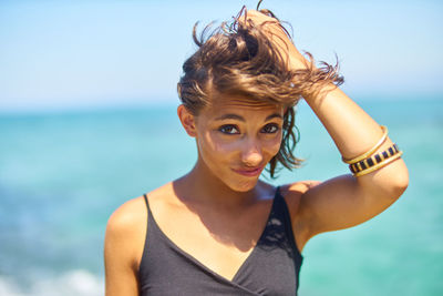 Close-up portrait of young woman standing against sea