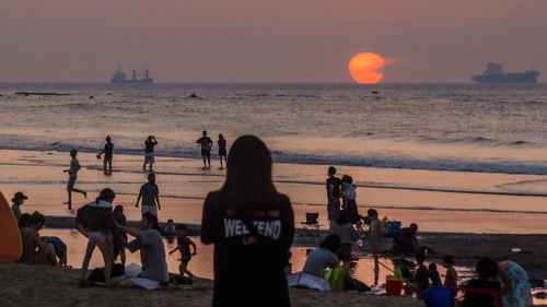 People on beach against sky during sunset