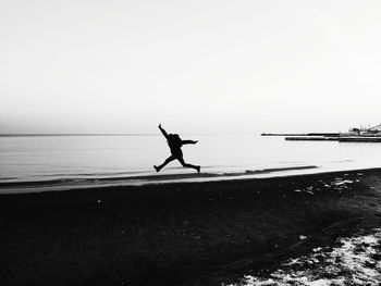 Silhouette person on beach against clear sky