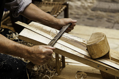 Midsection of man carving wood at workshop