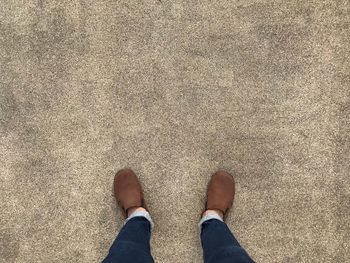 Low section of man standing on sand