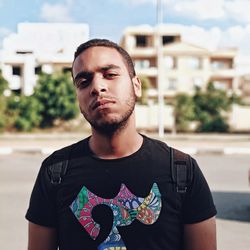 Portrait of young man standing against city