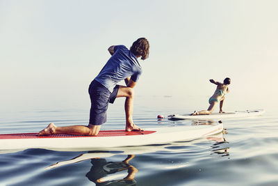 A group of standup paddle boarders doing yoga at sunrise in the fog