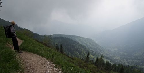 Scenic view of mountains with man standing on road against sky