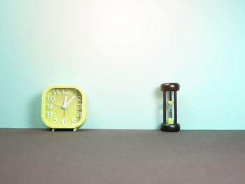 Close-up of clock on table against wall