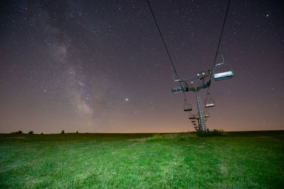 Low angle view of chair lift on field against sky