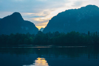 Scenic view of lake and mountains against sky at sunset