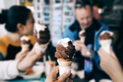 Cropped image of woman holding ice cream cone at restaurant