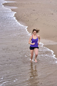 Full length of young woman running at beach