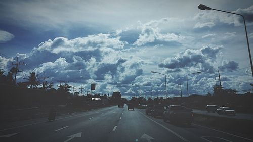 Cars on street in city against sky