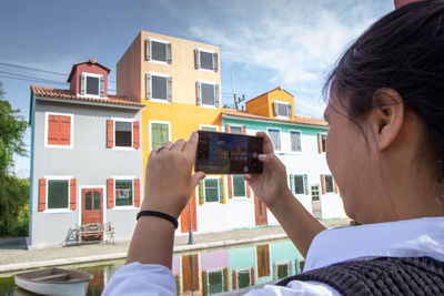 Rear view of woman photographing colorful building