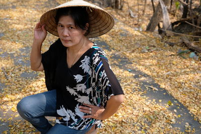 Mature woman wearing asian style conical hat on road during autumn