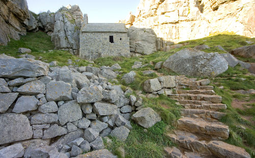 Stone wall by rock formation against sky