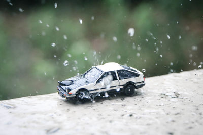 Close-up of water splashing on toy car over wall