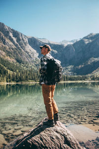 Woman standing by lake against mountain