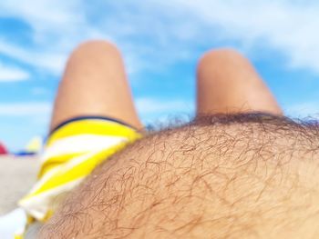 Midsection of man lying at beach against sky