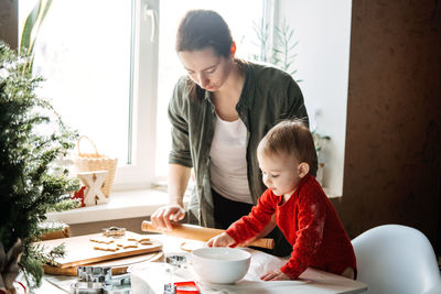 Happy mother and little baby toddler girl making christmas cookies in home kitchen. mother and
