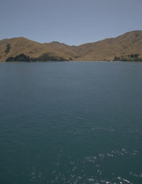 Scenic view of sea and mountains against clear sky