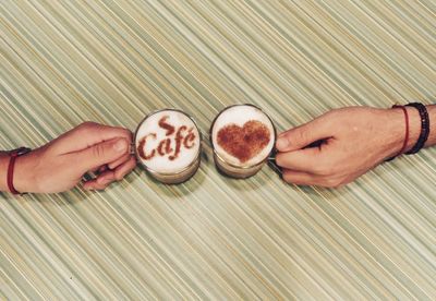 High angle view of hands holding coffee cup on table