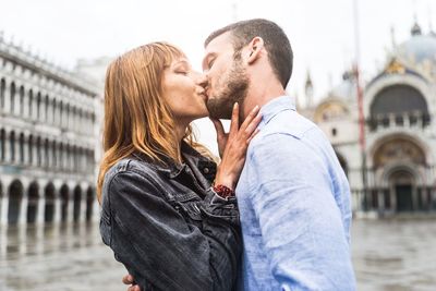 Midsection of couple kissing in city