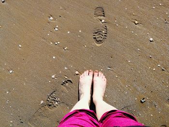 Low section of woman standing on sand