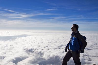 Man standing on snow covered landscape against sky