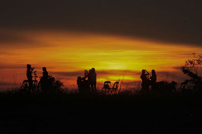 Silhouette men on field against sky during sunset