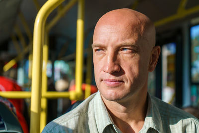 Travel safely by public transport. a young bald man looks through bus window.