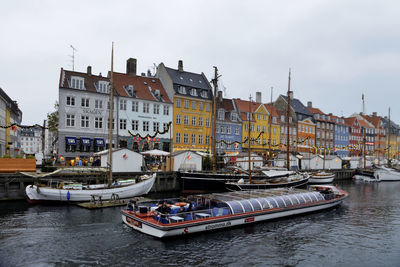 Sailboats moored on river by buildings in city against sky