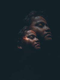 Close-up portrait of young woman against black background