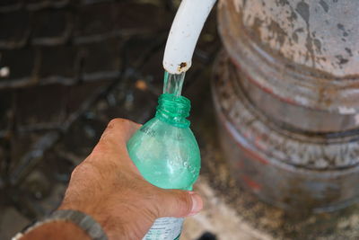 Cropped hand of man filling water bottle