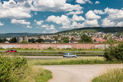 Road amidst field against sky in city