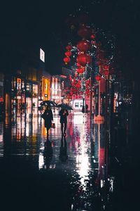 People walking on wet street during rainy season at night