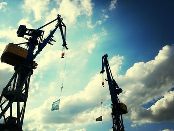 Low angle view of crane against cloudy sky