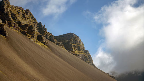 Low angle view of road amidst mountains against sky