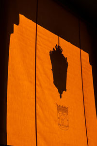 Low angle view of lantern hanging against orange wall