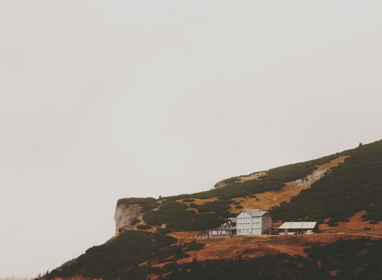 clear sky, copy space, building exterior, architecture, built structure, mountain, house, hill, tranquility, nature, landscape, tranquil scene, rock - object, residential structure, scenics, tree, beauty in nature, day, outdoors, no people