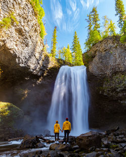 Rear view of man standing against waterfall