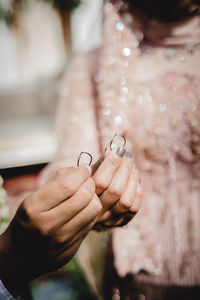 Midsection of bride and groom holding rings