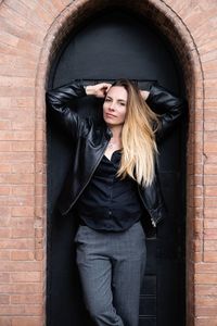 Portrait of beautiful woman standing amidst arch against wall